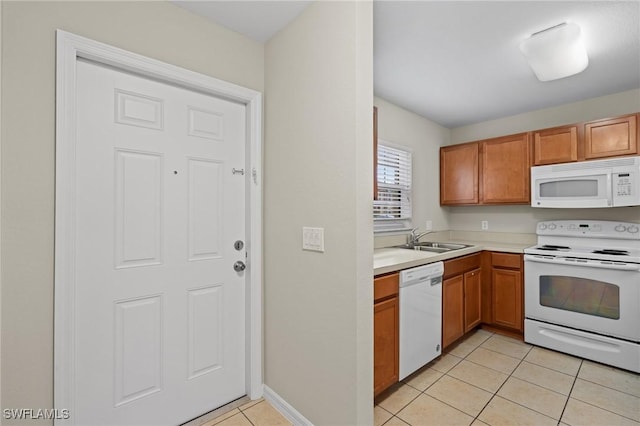 kitchen featuring a sink, white appliances, brown cabinetry, light countertops, and light tile patterned floors