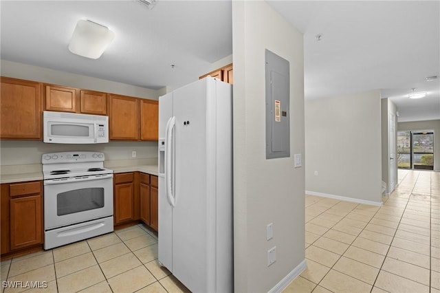 kitchen with white appliances, light tile patterned flooring, brown cabinetry, light countertops, and baseboards