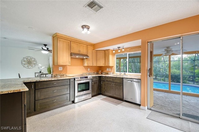 kitchen with sink, a textured ceiling, kitchen peninsula, and stainless steel appliances