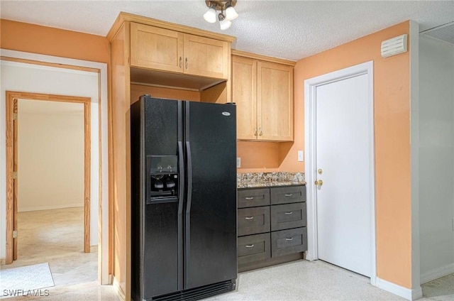 kitchen featuring light brown cabinetry, light stone countertops, a textured ceiling, and black fridge with ice dispenser