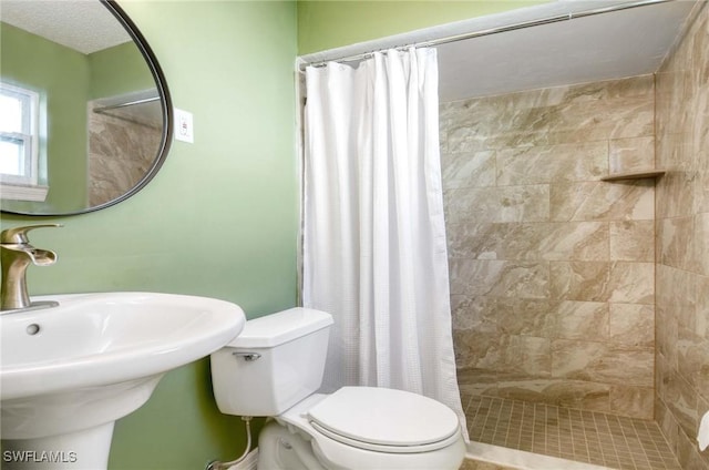 bathroom featuring toilet, sink, and a shower with shower curtain