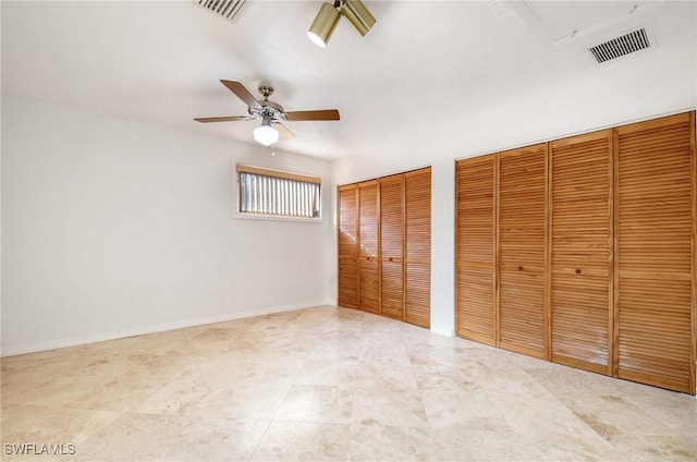 unfurnished bedroom featuring ceiling fan and multiple closets