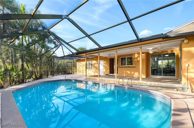 view of swimming pool with ceiling fan, a patio area, and glass enclosure