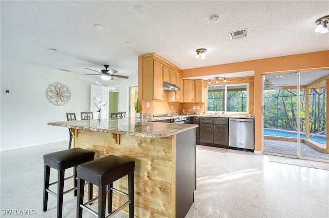 kitchen with ceiling fan, a breakfast bar, kitchen peninsula, stainless steel appliances, and a textured ceiling