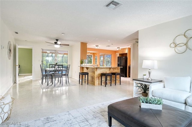 living room featuring ceiling fan and a textured ceiling