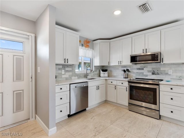 kitchen featuring backsplash, stainless steel appliances, sink, and white cabinets