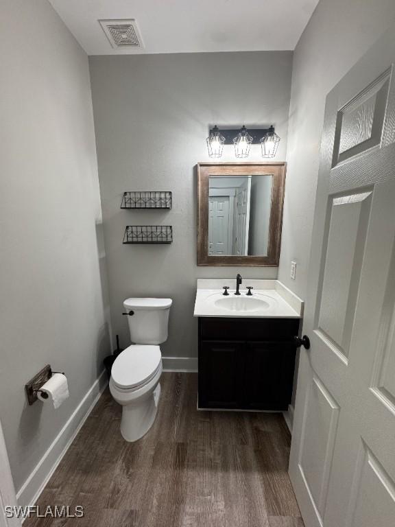 bathroom featuring toilet, vanity, and hardwood / wood-style flooring