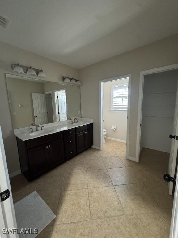 bathroom with toilet, vanity, and tile patterned floors