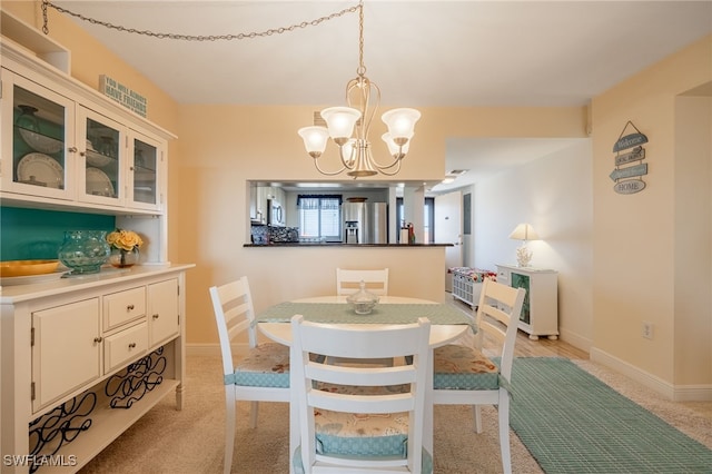 carpeted dining area with an inviting chandelier