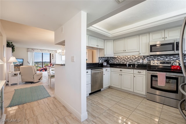 kitchen with tasteful backsplash, stainless steel appliances, a raised ceiling, a chandelier, and white cabinetry