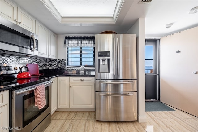 kitchen with backsplash, plenty of natural light, stainless steel appliances, and a tray ceiling