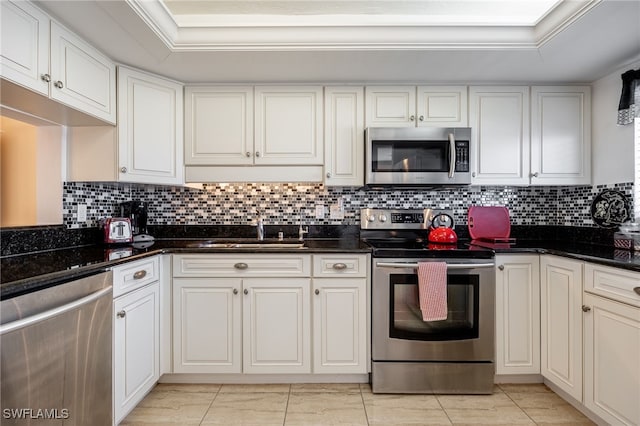 kitchen with a tray ceiling, white cabinetry, sink, and appliances with stainless steel finishes