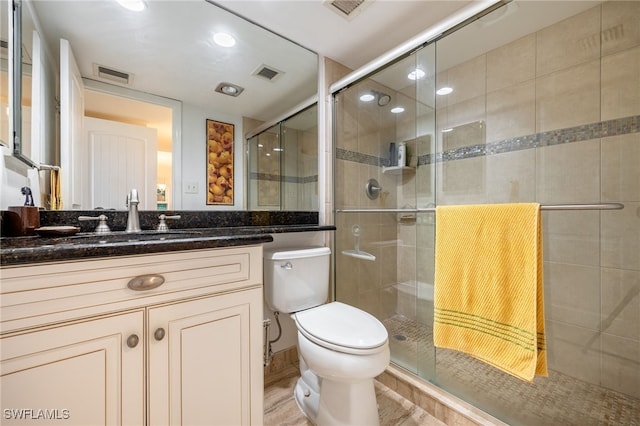 bathroom featuring vanity, a shower with shower door, and toilet