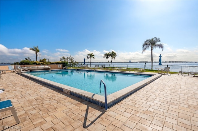 view of pool with a water view and a patio