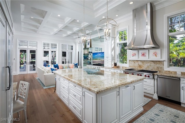 kitchen with french doors, exhaust hood, pendant lighting, white cabinets, and a center island