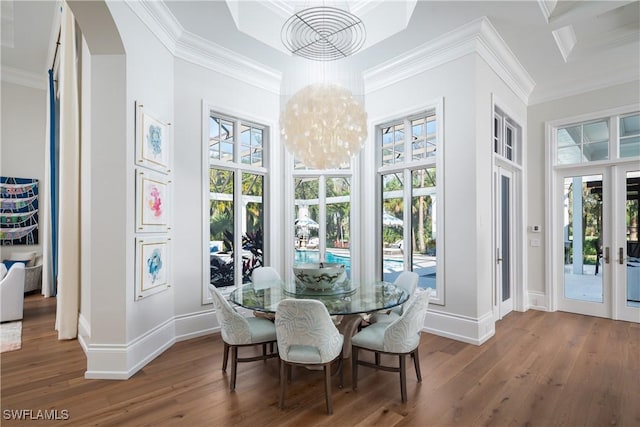 dining room with hardwood / wood-style floors, an inviting chandelier, crown molding, and french doors