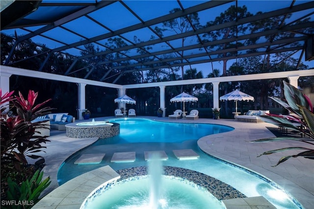 view of swimming pool with glass enclosure, an in ground hot tub, pool water feature, and a patio