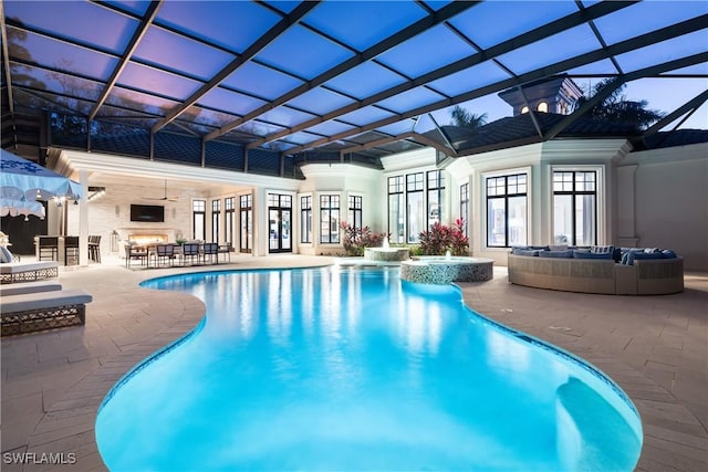 view of pool featuring glass enclosure, outdoor lounge area, and a patio