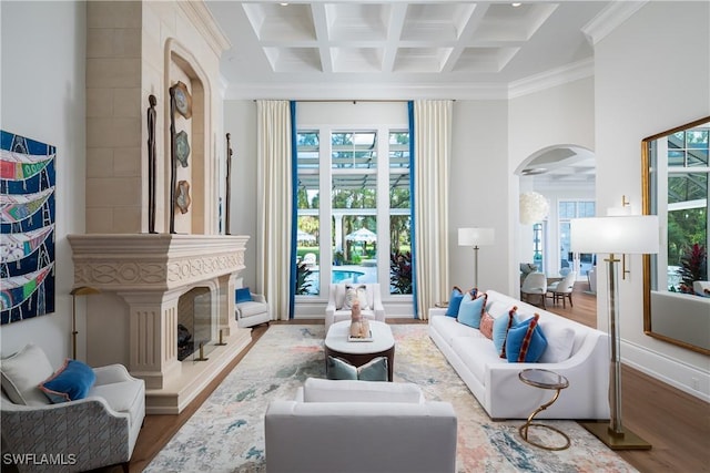 living room with crown molding, beamed ceiling, coffered ceiling, and light wood-type flooring