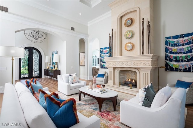 living room featuring crown molding, french doors, a high end fireplace, and hardwood / wood-style floors