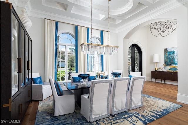 dining space featuring wood-type flooring, a healthy amount of sunlight, a notable chandelier, and coffered ceiling