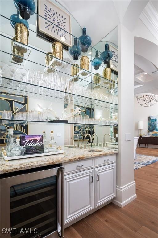 bar with white cabinets, dark hardwood / wood-style floors, light stone countertops, and wine cooler