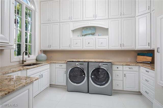 washroom featuring cabinets, light tile patterned floors, washing machine and clothes dryer, and sink