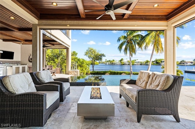 view of patio / terrace with ceiling fan, a water view, and an outdoor living space with a fire pit