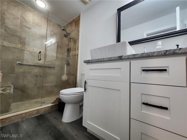 bathroom featuring vanity, toilet, wood-type flooring, and a shower with door