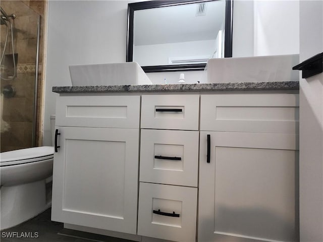 bathroom featuring vanity, toilet, and walk in shower