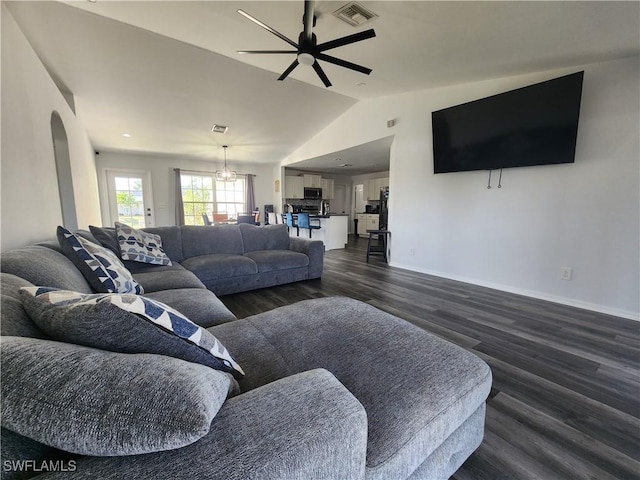 living room with ceiling fan with notable chandelier, dark hardwood / wood-style flooring, and lofted ceiling