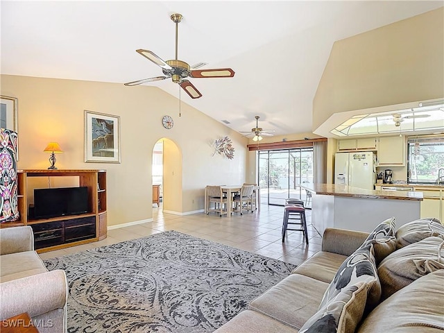 living room featuring lofted ceiling, ceiling fan, light tile patterned floors, and sink