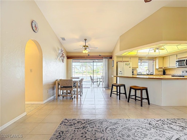 dining space featuring ceiling fan, light tile patterned floors, and lofted ceiling