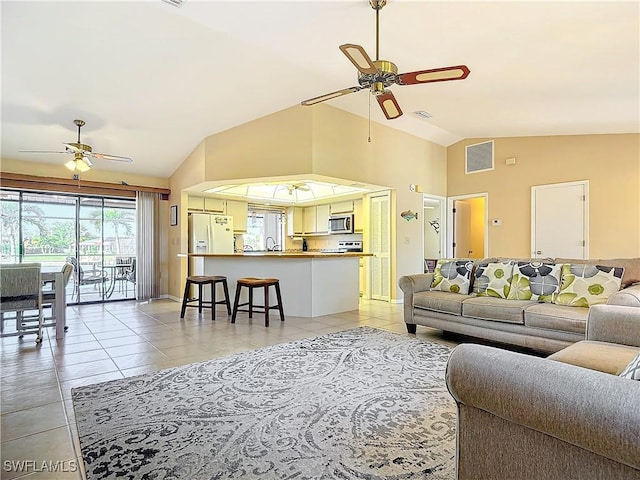 living room featuring lofted ceiling, ceiling fan, light tile patterned floors, and sink