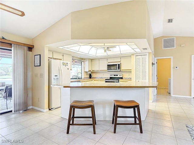 kitchen with a kitchen breakfast bar, ceiling fan, a healthy amount of sunlight, and appliances with stainless steel finishes