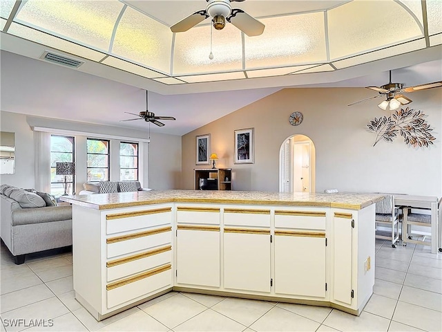 kitchen featuring kitchen peninsula, light tile patterned floors, and vaulted ceiling