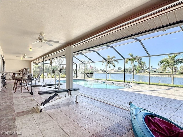 view of pool with a patio, a water view, glass enclosure, and ceiling fan