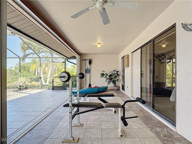 exercise room with ceiling fan and a textured ceiling