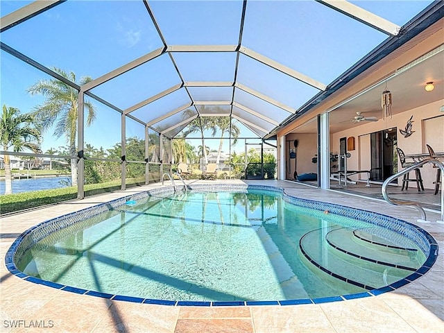 view of pool with a lanai, a water view, ceiling fan, and a patio area