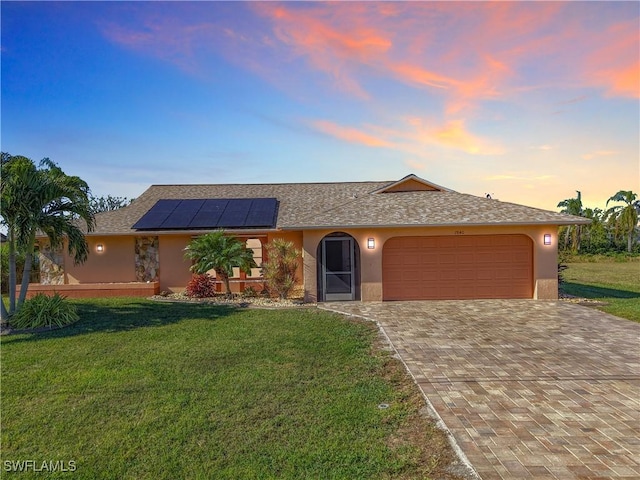 ranch-style house featuring solar panels, a yard, and a garage