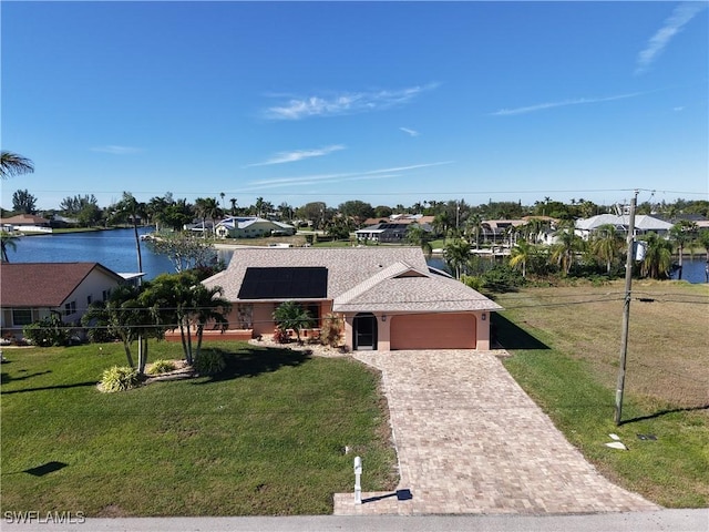 view of front of house with a water view, a garage, a front yard, and solar panels