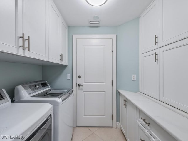 washroom with cabinets, light tile patterned floors, and washing machine and clothes dryer