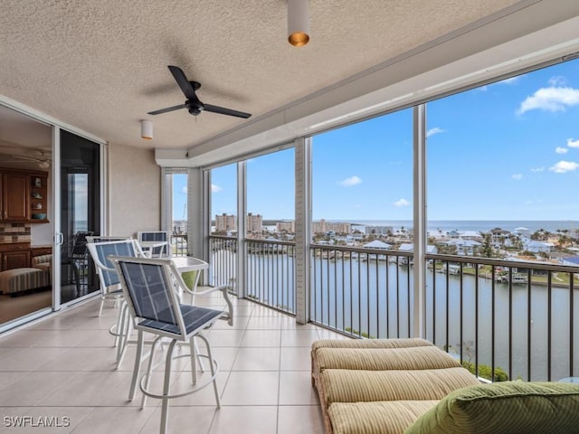 sunroom featuring ceiling fan and a water view