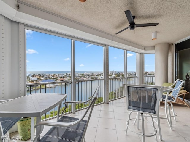 sunroom with a water view and ceiling fan