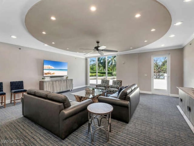 carpeted living room featuring a raised ceiling and ceiling fan