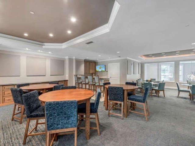 dining space featuring carpet flooring, a raised ceiling, and ornamental molding