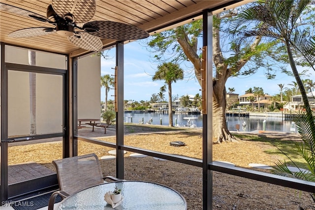 sunroom featuring ceiling fan and a water view