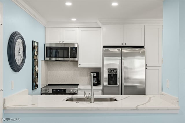 kitchen featuring white cabinetry, ornamental molding, light stone counters, and appliances with stainless steel finishes