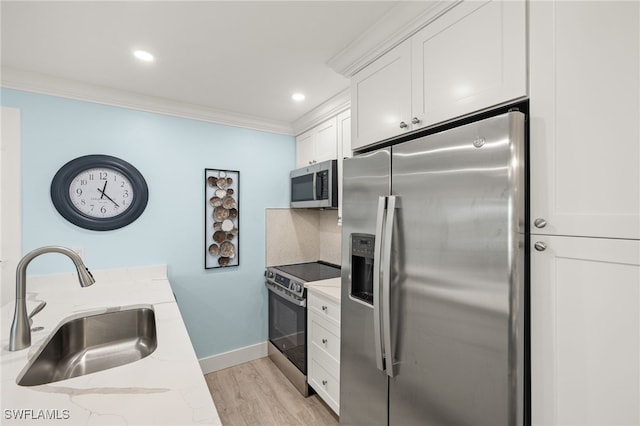 kitchen with white cabinets, sink, ornamental molding, light stone counters, and stainless steel appliances