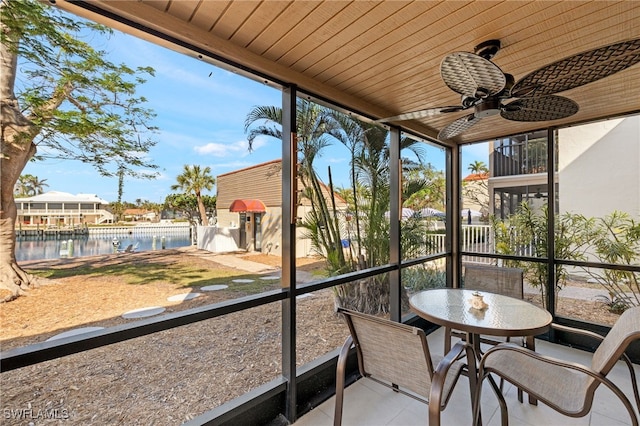 sunroom featuring ceiling fan, a water view, wood ceiling, and plenty of natural light